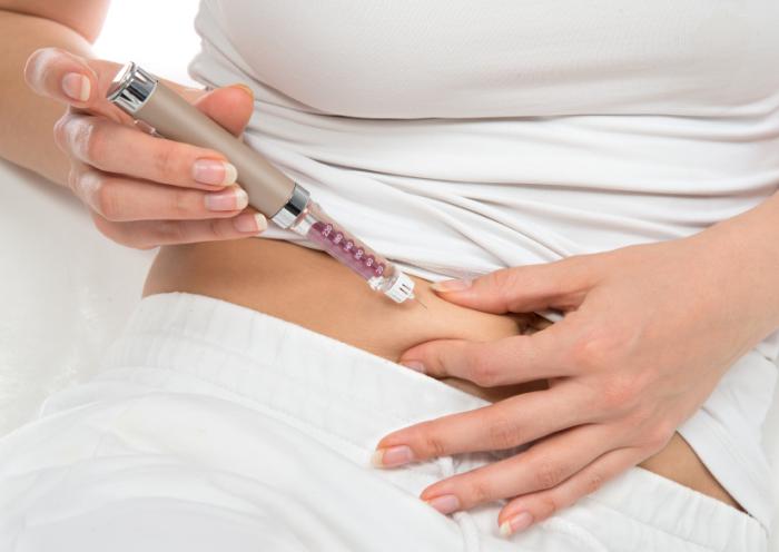 Uma mulher injeta insulina em sua barriga.