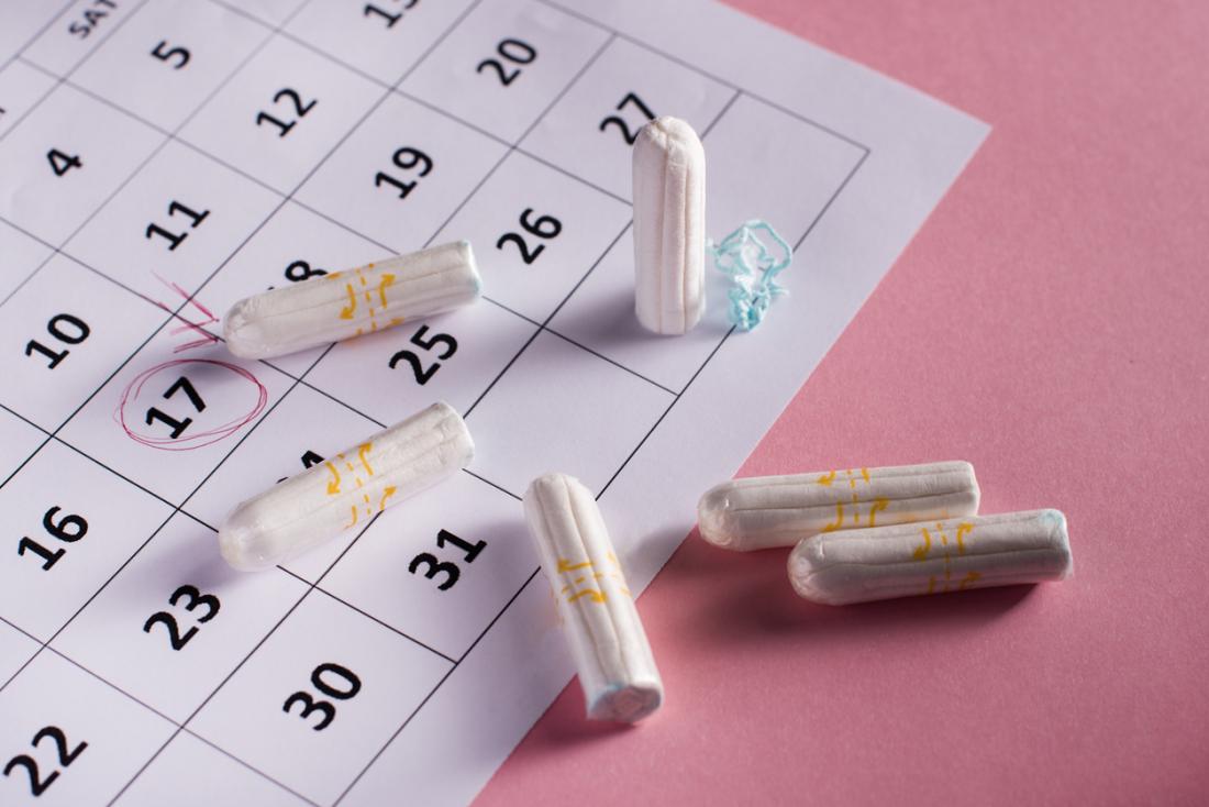 Tampons oben auf den Kalender, der Menstruationszyklus markiert.