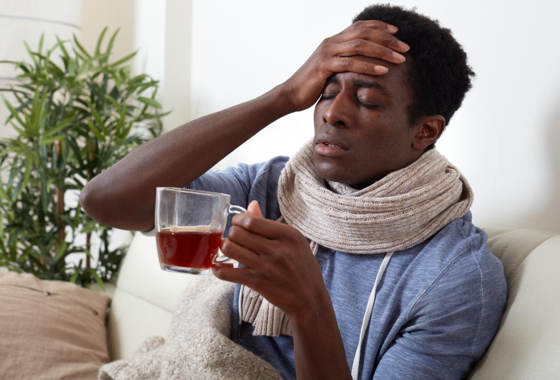 Човек с треска и студени тръпки, причинени от пневмония, пие билков чай.