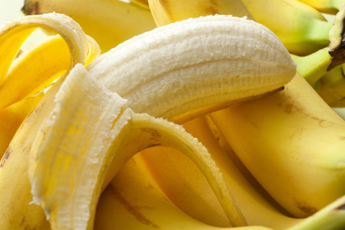 バナナの束の上に半分の皮を剥いたバナナ。