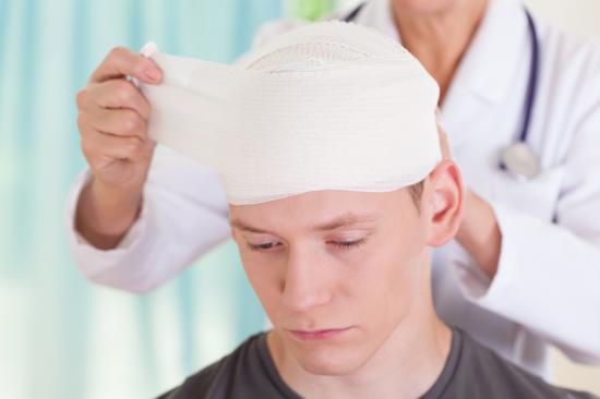 傷ついた男の頭を包帯する医者