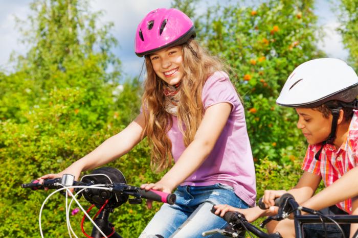 [crianças usando capacetes e andando de bicicleta]