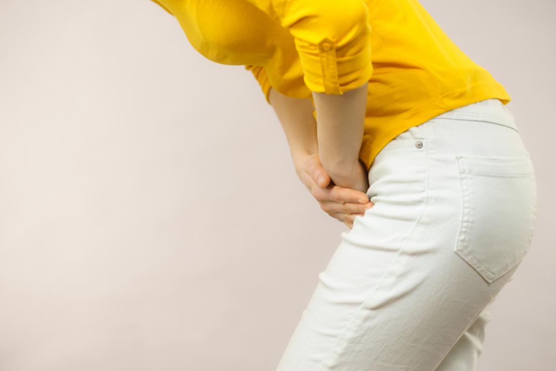 A pessoa com endometriose da bexiga dobrou-se segurando a parte inferior do abdómen com dor.