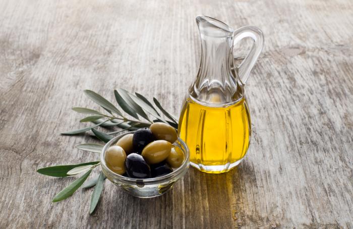 Un pichet d'huile d'olive avec un plat d'olives.