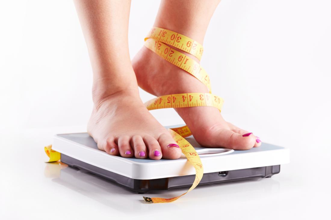 女性は、測定テープで秤に立っています。タモキシフェンは体重増加を引き起こすか？