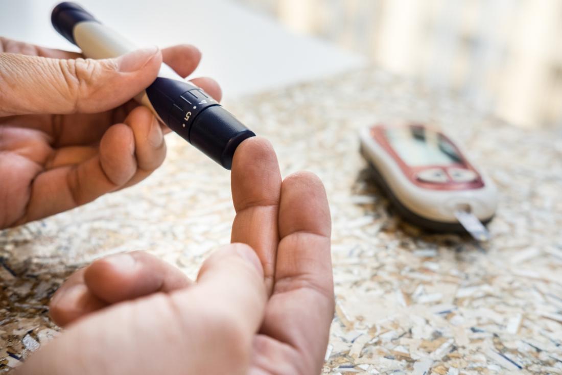 die Hände des diabetischen Mannes, die Blutzuckerspiegel mit einem Glukosemeter überprüfen