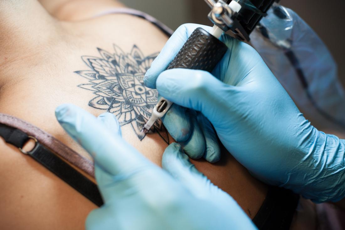 Lady fazendo uma tatuagem nas costas