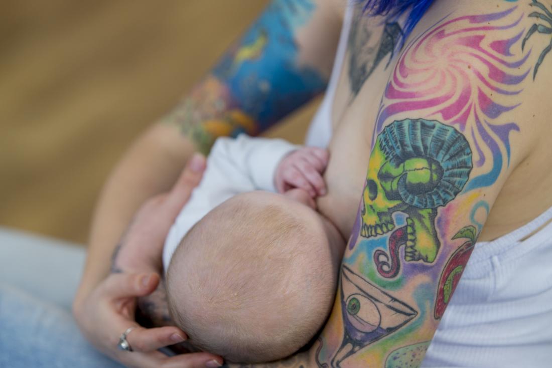 Senhora com tatuagens amamentando seu bebê
