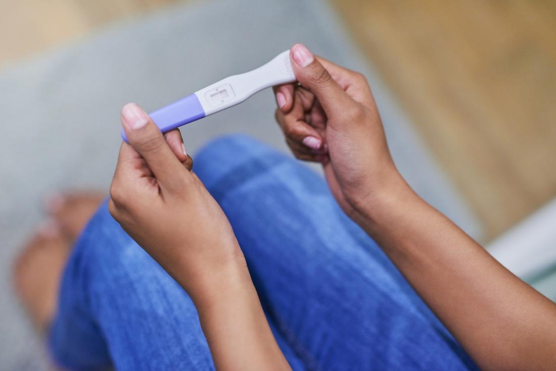 Femme tenant le bâton de test de grossesse.