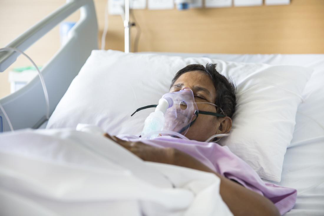 Bệnh nhân nằm trên giường bệnh với máy thở.