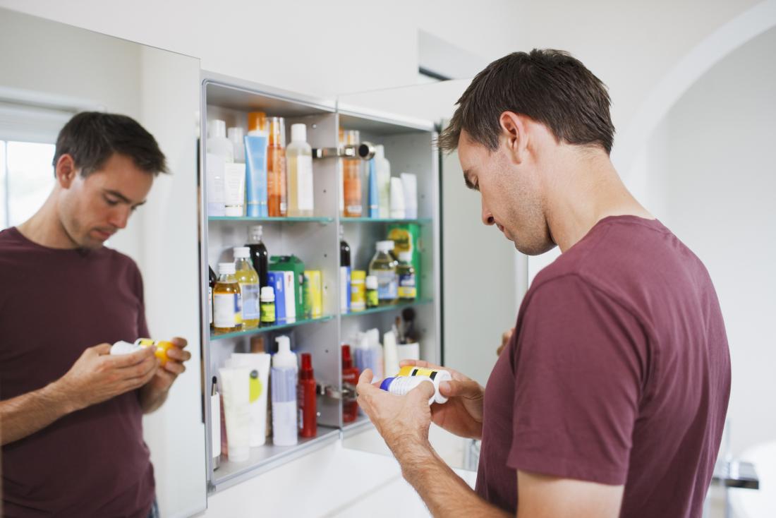 Homem que olha frascos da pílula de seu gabinete de medicina.