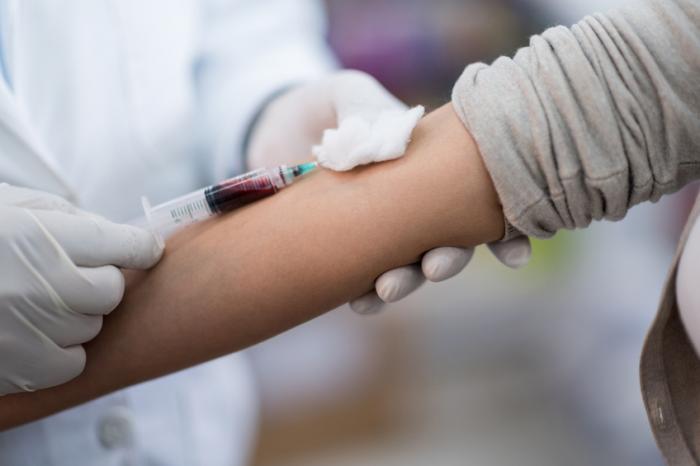 Ein Arzt benutzt eine Nadel, um Blut aus einem Arm zu entnehmen