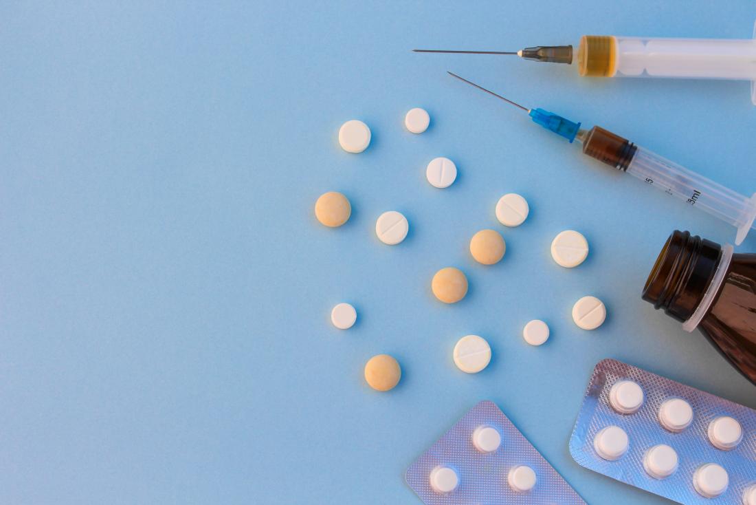 pílulas e seringas em fundo azul