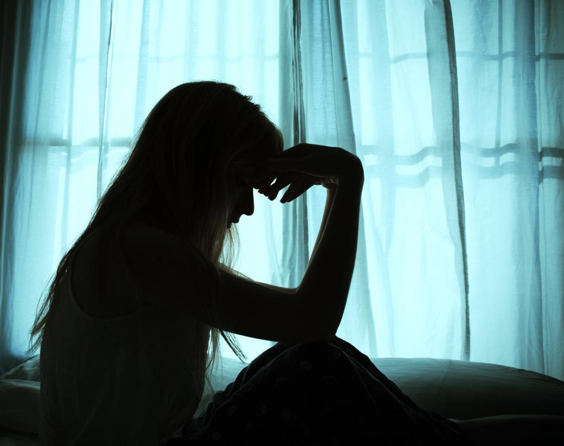 karanlıkta bir pencere tarafından oturan bir üzgün kadın