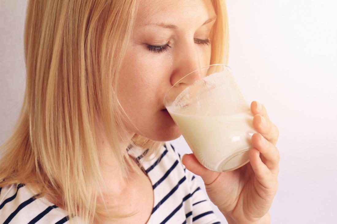 Mulher bebendo iogurte probiótico.