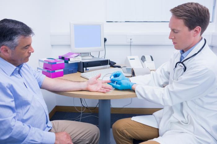 Un medico controlla i livelli di zucchero nel sangue di un uomo.