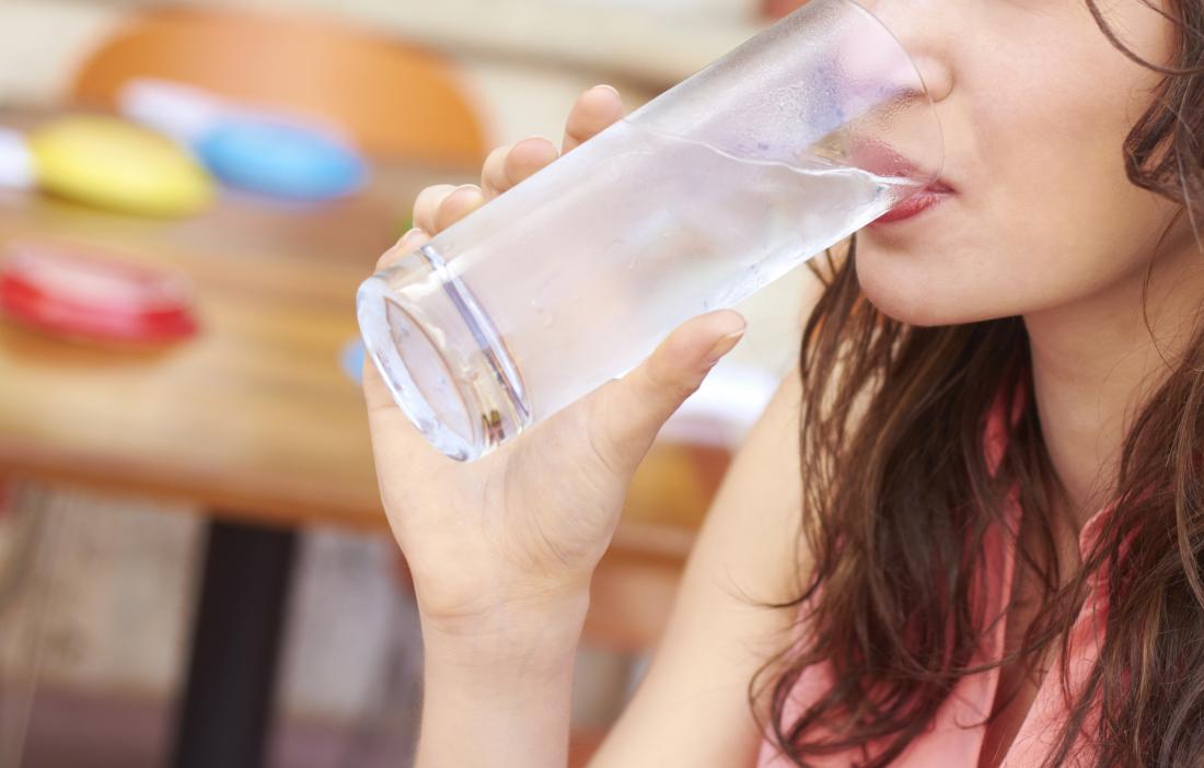 млада жена, пиеща чаша вода