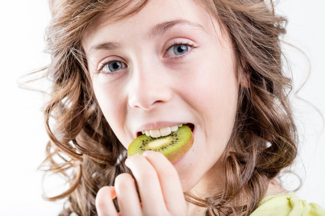 ragazza che mangia frutta kiwi