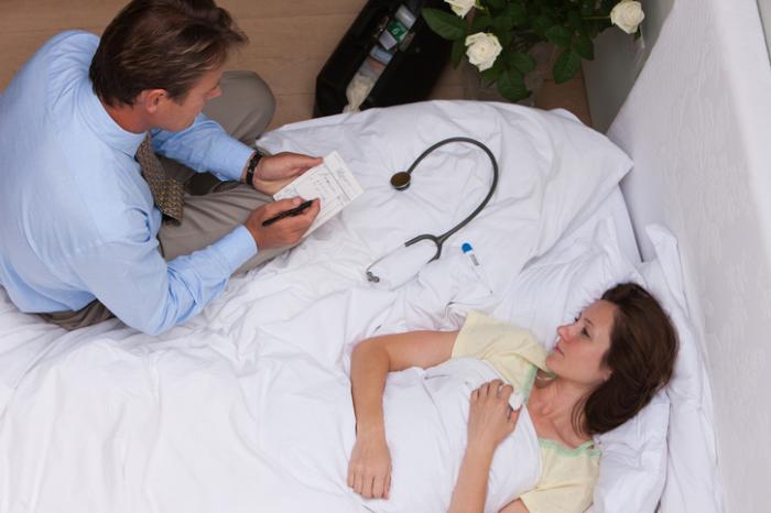 Yatakta hasta olan bir hastayı ziyaret eden doktor
