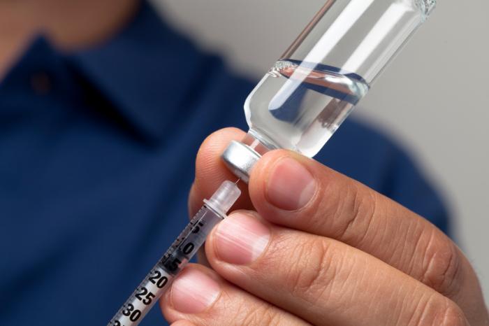 Una siringa è inserita in una piccola bottiglia di insulina