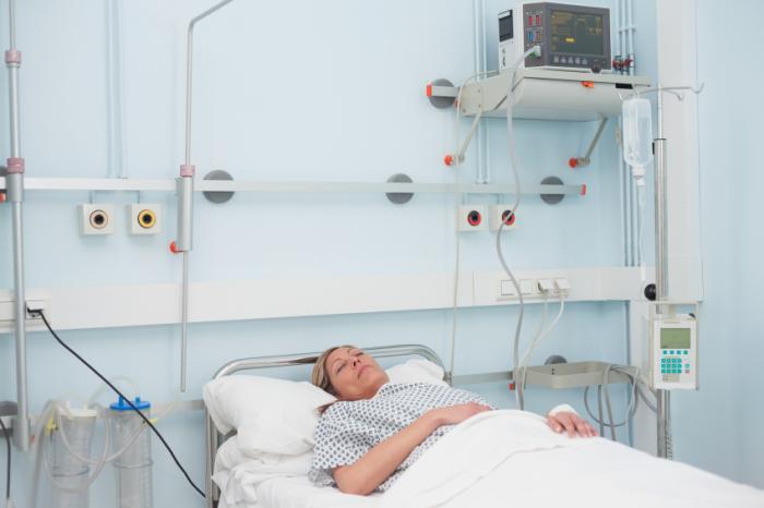Eine Frau in einem Koma auf einem Krankenhausbett.
