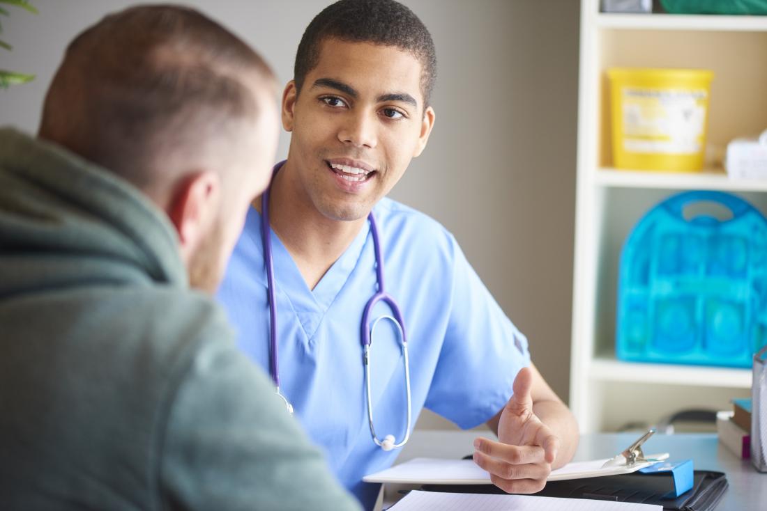 giovane medico di sesso maschile che parla con un giovane paziente maschio su un impianto penieno