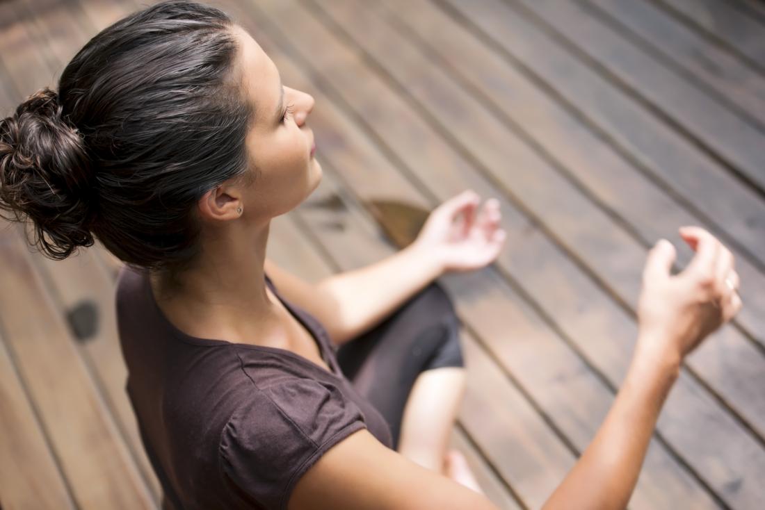 Una donna che medita all'esterno può aiutare a ridurre lo stress che può causare una breve fase luteale