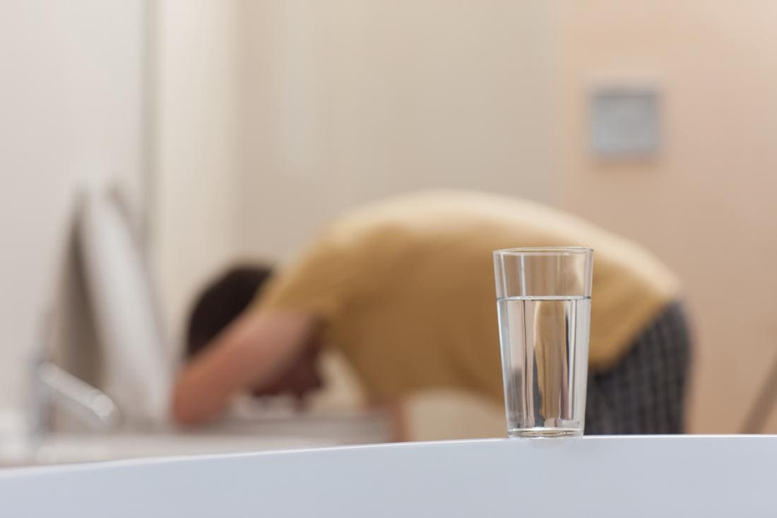 homme vomissant dans les toilettes