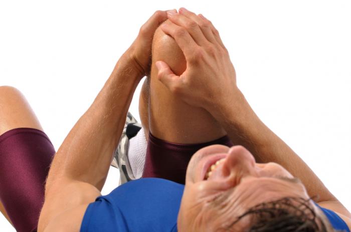 Ein Mann auf dem Boden mit starken Knieschmerzen.
