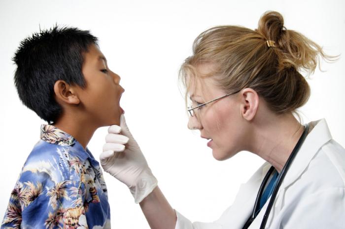Bir doktor çocuğun boğazını inceler.