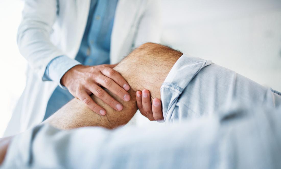 Behandeln Sie das Halten eines Patientenknies, das versucht, innere Knieschmerz zu bestimmen