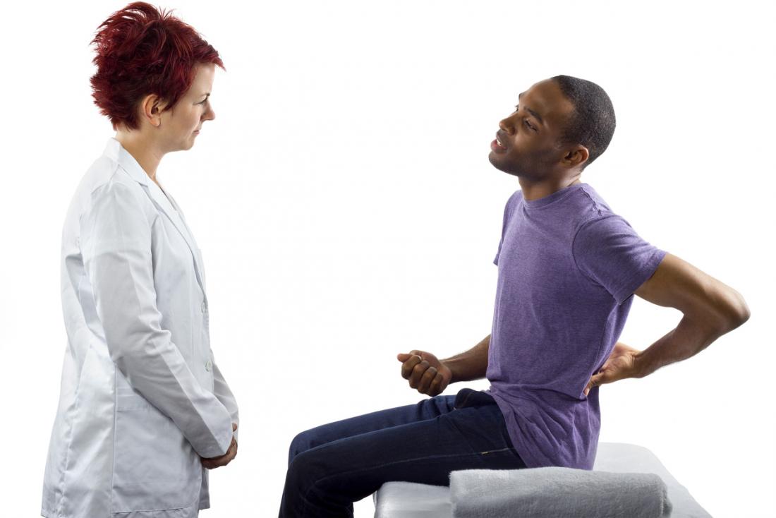 Mann mit Rückenschmerzen spricht mit dem Arzt