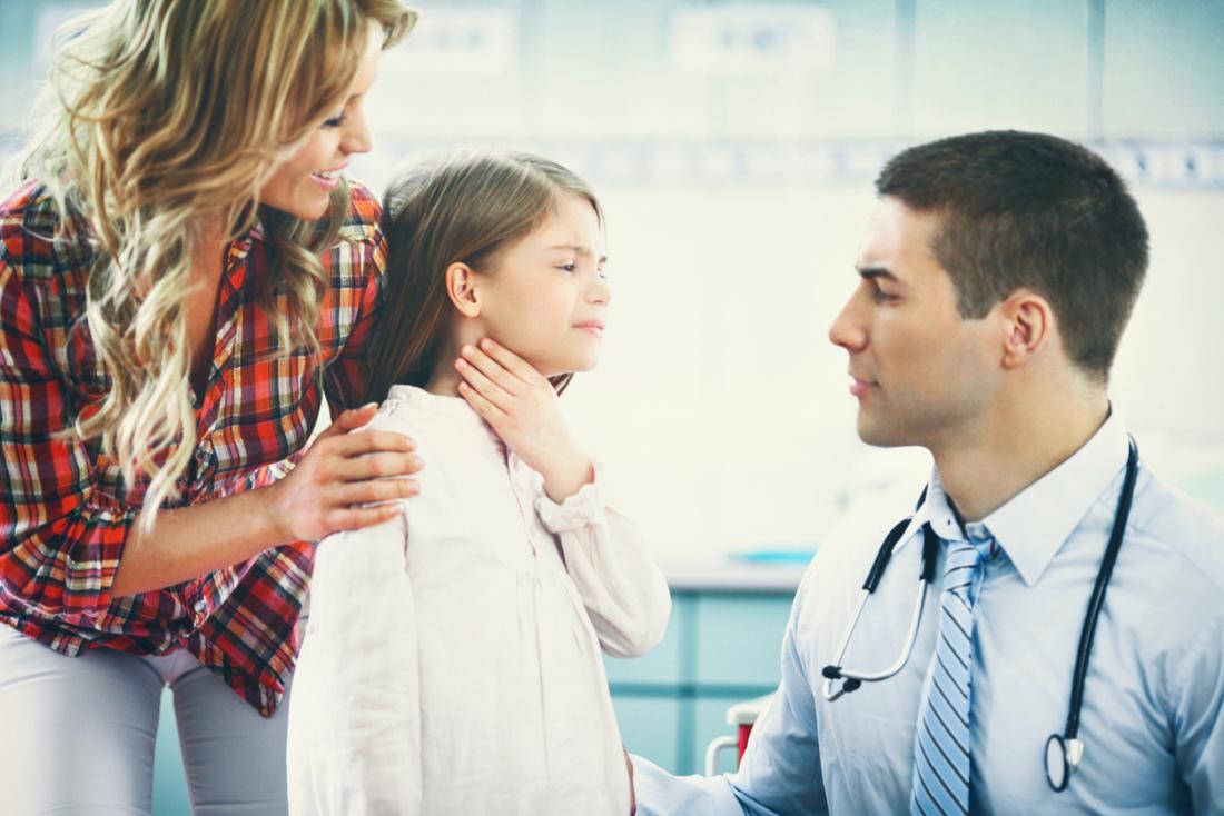 Дете с болка в гърлото с родител в кабинета на педиатър.