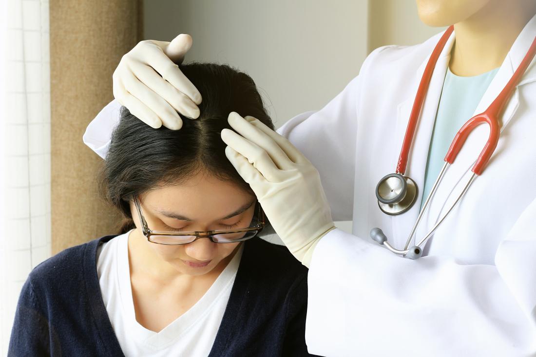 Жена, която има скалп, инспектирана за акне на скалпа от дерматолог