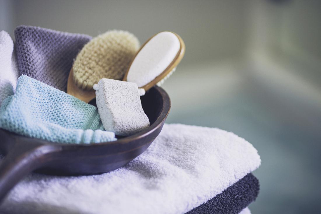 Forniture da bagno nella ciotola sopra gli asciugamani, compresi loofah, scrub, spazzola per la pelle.