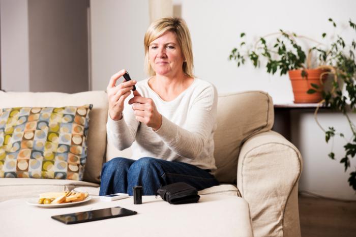 [mulher verificando o nível de açúcar no sangue antes de comer]