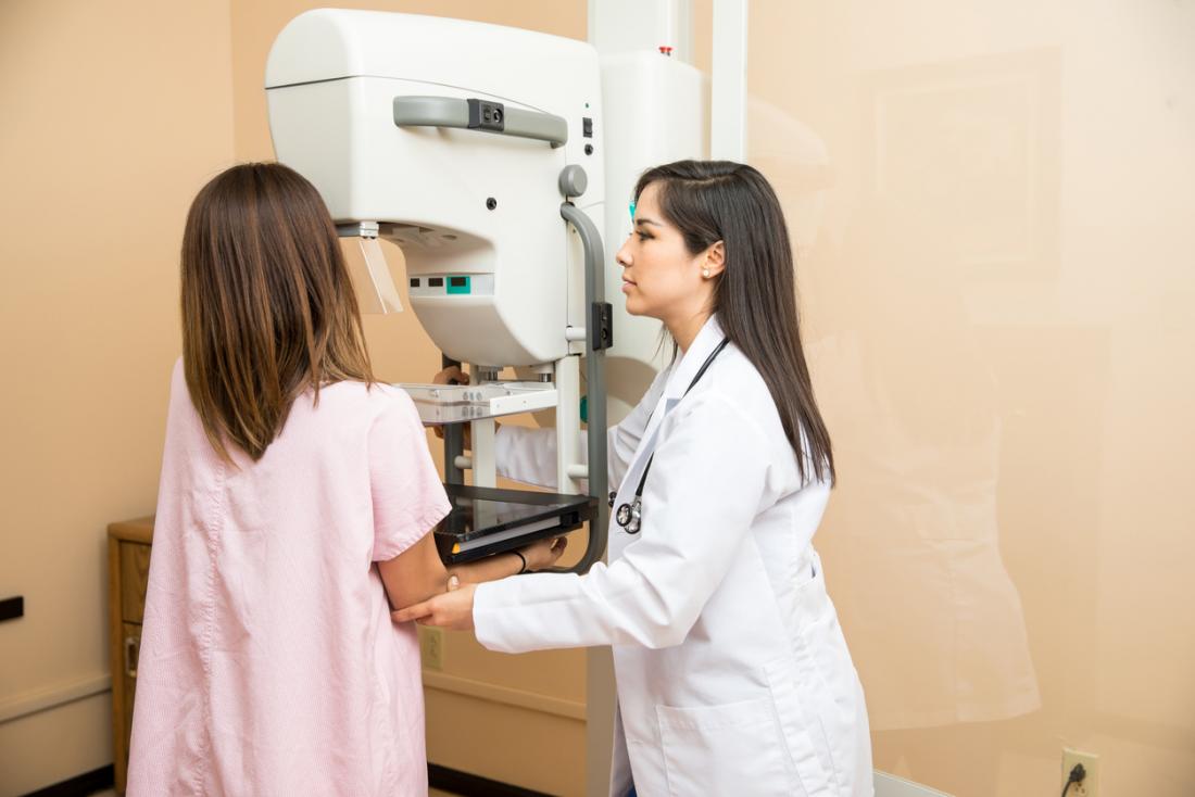 [Heilpraktiker hilft einer Frau, eine Mammogrammmaschine zu benutzen]