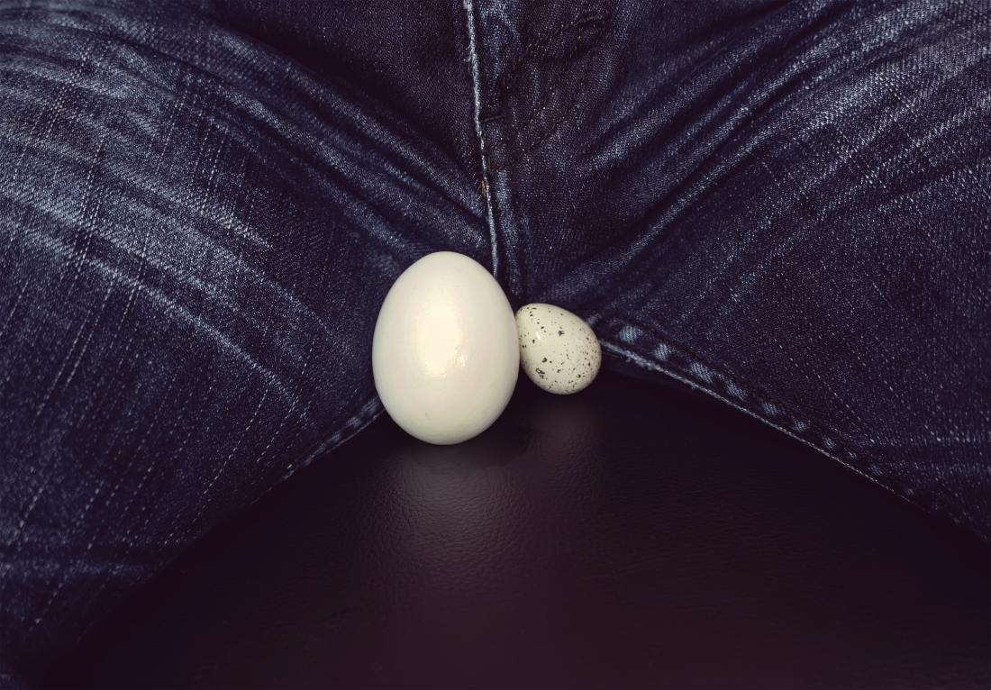 ジーンズの男性の股の近くにある2つの異なるサイズの卵で示されるもう1つの睾丸よりも大きな1つの睾丸