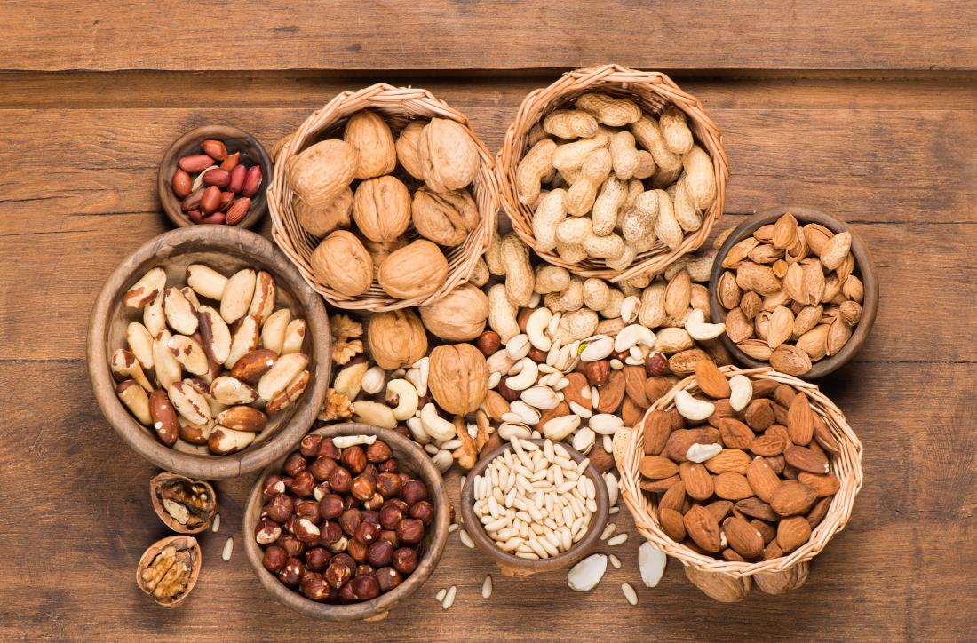 Các loại hạt khác nhau trong bát trên bàn gỗ.