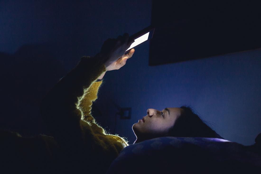 osoba patrząc na jasny ekran telefonu w nocy