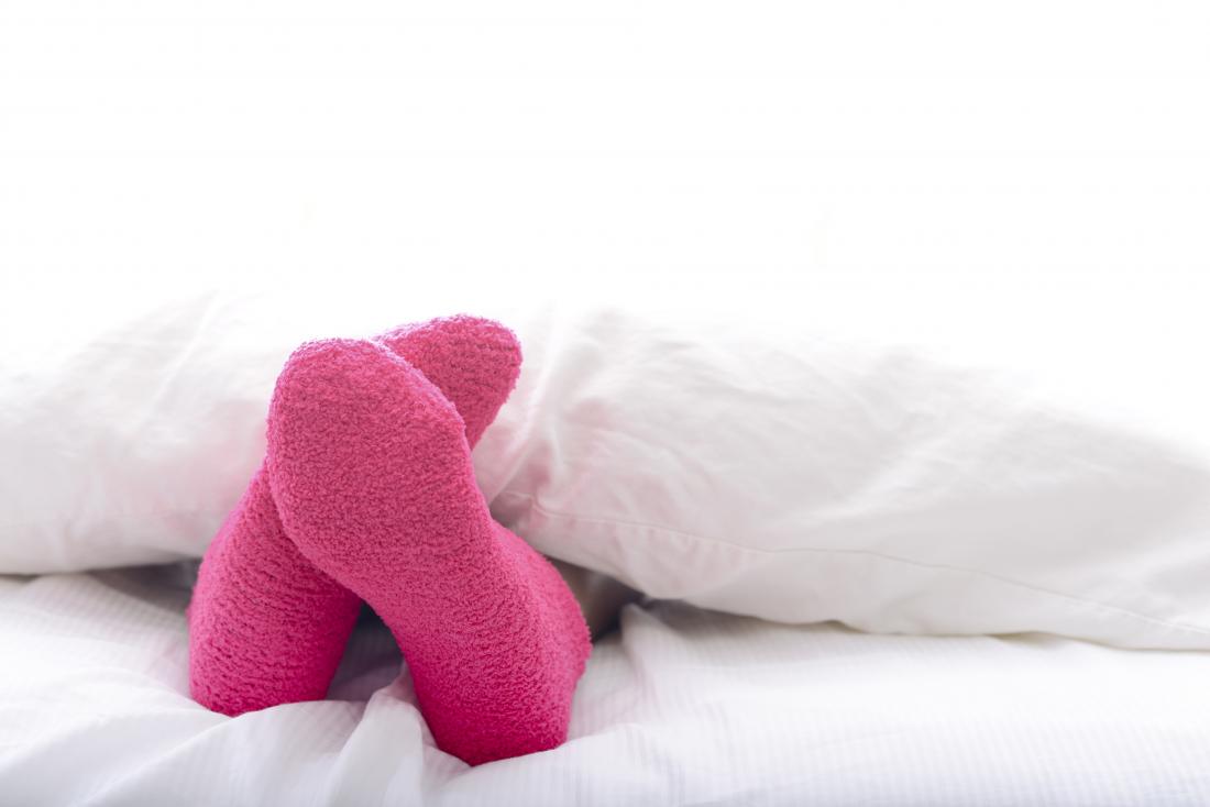 Yataktaki kişi pembe çoraplarla uyumaya, yorgandan dışarı çıkarak.