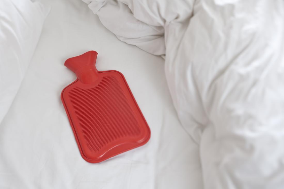 Beyaz yatakta kırmızı sıcak su şişesi.
