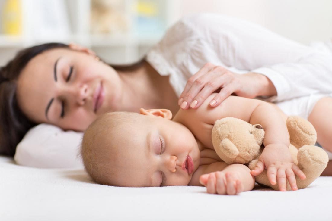 Frau schläft neben ihrem Baby