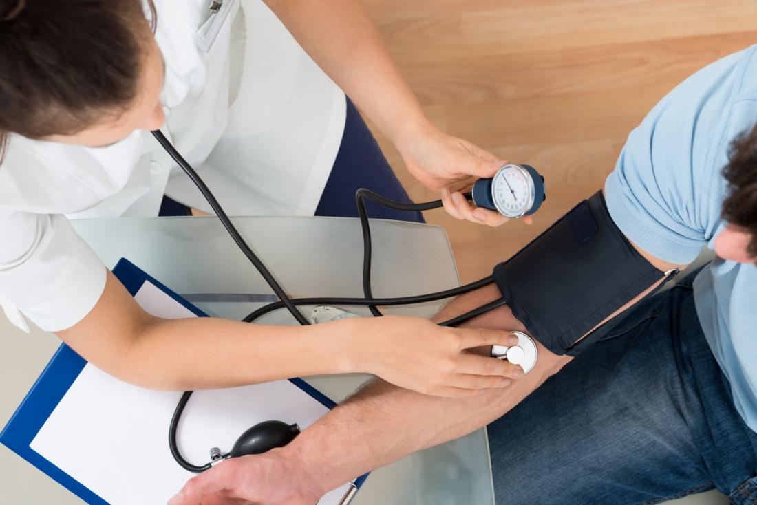 Vogelperspektive der weiblichen Krankenschwester Blutdruck des männlichen Patienten messend.