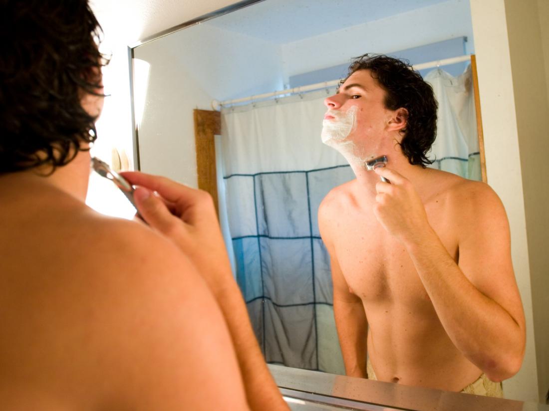 Mann rasiert sich im Badezimmer