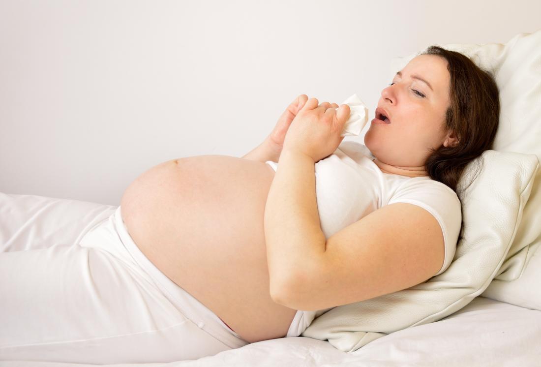 妊娠中の肺炎の女性は、組織でベッドに横たわっています。