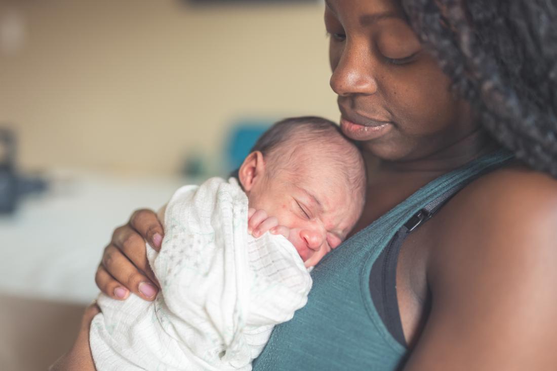 жена, държаща новородено, загрижено за кървене след раждане