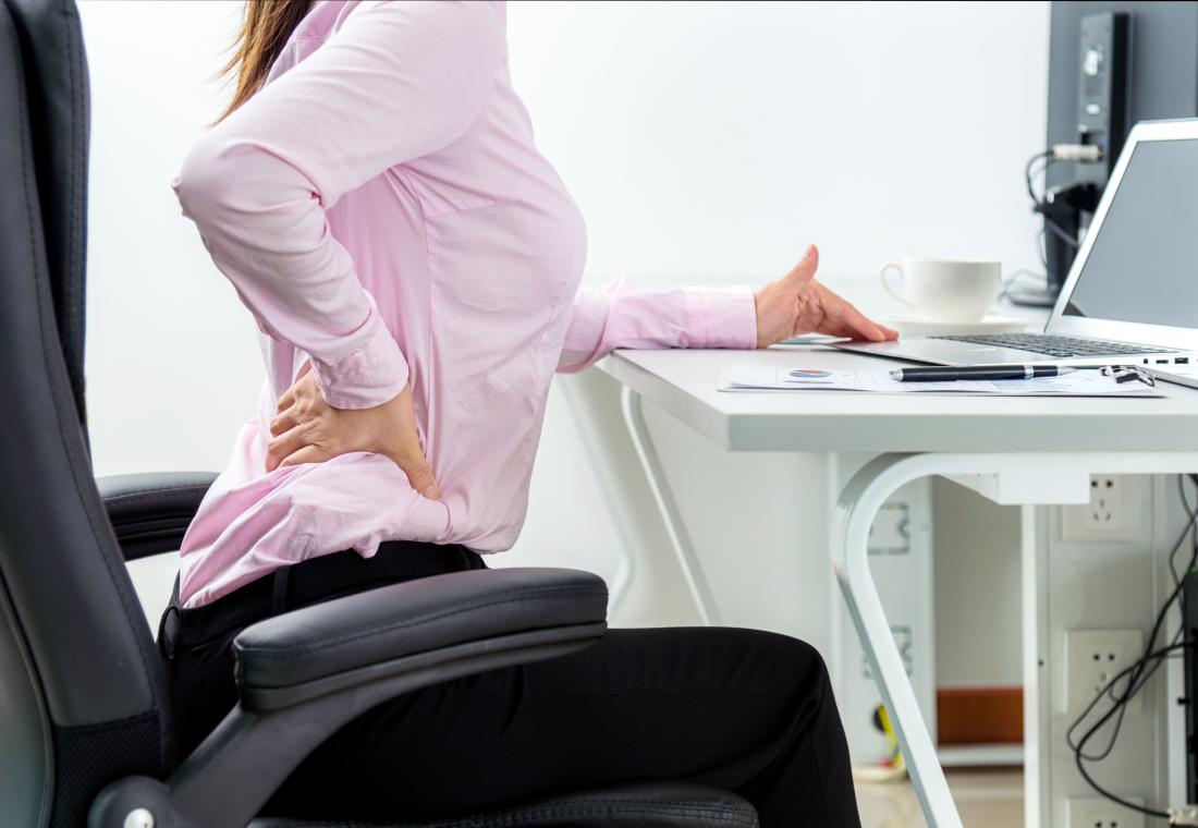 クアドラトゥス腰痛 - 腰痛が机に座っている女性