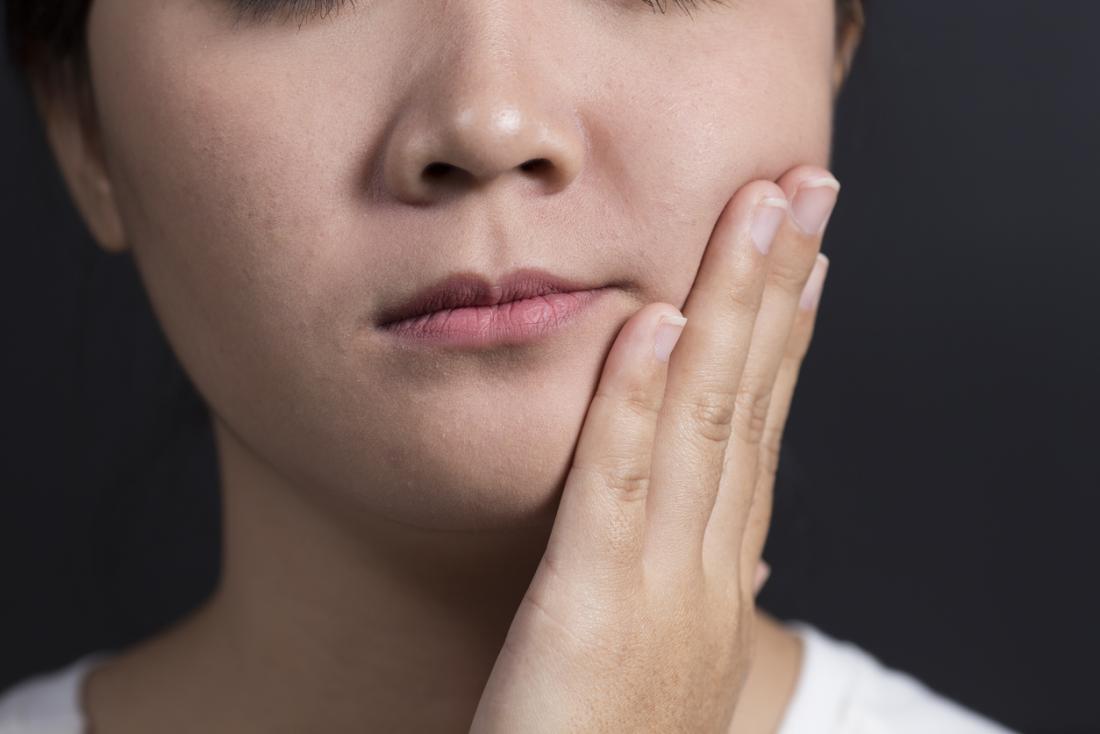 唾液腺が位置する顎の側面を保持する女性