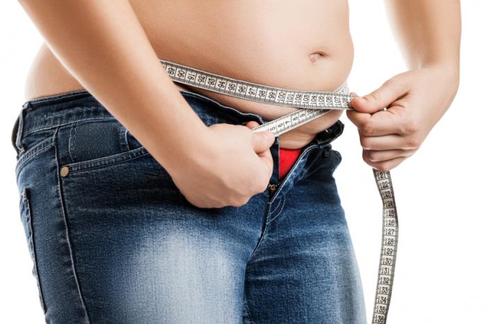 Una donna in sovrappeso che misura la vita